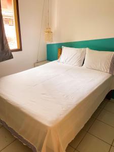 ein großes Bett mit weißer Bettwäsche und Kissen in der Unterkunft Casa Mar in Praia do Forte