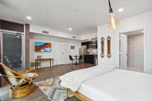 een witte slaapkamer met een bed en een stoel bij Tempe Lofty Studios in Tempe