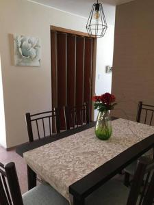 een eettafel met een vaas met bloemen erop bij Hermosa casa tranquila en la ciudad in Mendoza