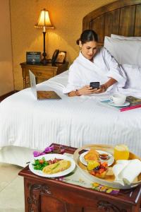 une femme qui se couche au lit avec un plateau de nourriture dans l'établissement Uzhupud Garden Hotel & Lodge, à Paute