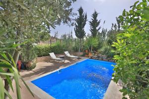 een blauw zwembad met 2 stoelen en bomen bij Charmant appartement avec terrasse privee a fes medina in Fès