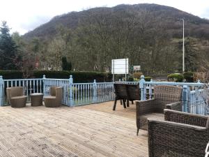 a deck with chairs and a fence with a mountain at Distillery Guest House in Fort William