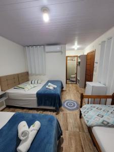 two beds in a small room with blue sheets at Pousada Pontal da Armação in Penha
