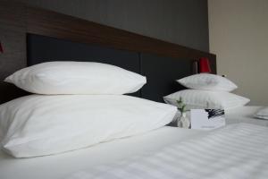 łóżko z białymi poduszkami na górze w obiekcie Best Western Plus Plaza Hotel Graz w Grazu