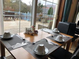 a wooden table with utensils on it with a view of a deck at Distillery Guest House in Fort William