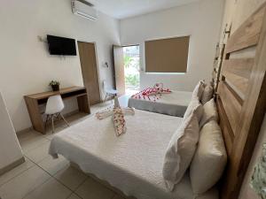 a hotel room with two beds and a television at Condominios JAROJE in Santa Cruz Huatulco