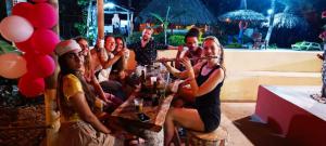 grupa ludzi siedzących przy stole z drinkami w obiekcie Cabañas San Sebastian Palomino Beach Hostel w mieście Palomino