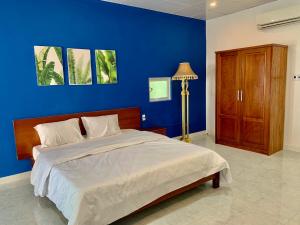 a blue bedroom with a bed and a blue wall at Charming and Spacious Beach Homestay 4 Rooms 1 Pool Entire Palace in Hà Bàng