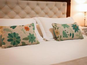een bed met witte lakens en kussens met bloemen erop bij Casa de campo Doña Ana 