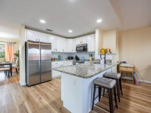 a kitchen with a stainless steel refrigerator and wooden floors at Englewood, Manasota Keys - 2 Bedroom Luxury Villa, Pool, Game room, 6 min to Beaches next to Canal in Englewood