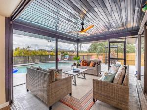 a covered patio with chairs and a table and a pool at Englewood, Manasota Keys - 2 Bedroom Luxury Villa, Pool, Game room, 6 min to Beaches next to Canal in Englewood
