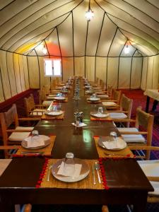 Merzouga heart camp في مرزوقة: طاولة طويلة في خيمة مع طاولات وكراسي