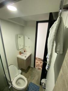 uma casa de banho com um WC, um lavatório e um espelho. em Lujoso apartamento amoblado en Coveñas cerca a la playa em Coveñas