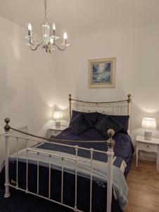 a bedroom with a bed with purple sheets and a chandelier at Shadow's Cottage situated in Fishertown, Nairn. in Nairn