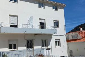 um edifício branco com uma varanda em cima em Moradia Félix - Apartamento Félix em Manteigas