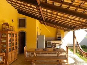 eine Küche mit gelben Wänden, einem Tisch und einem Kühlschrank in der Unterkunft Casa Três Amores in Búzios