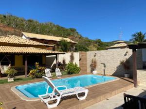 a swimming pool with two lounge chairs and a house at Casa Três Amores in Búzios