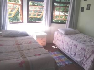 dwa łóżka w pokoju z dwoma oknami w obiekcie Centro - São Francisco Xavier - Casa Agradável w mieście São Francisco Xavier