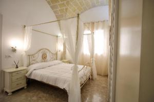 a white bedroom with a canopy bed and a window at AFFITTACAMERE I PACIORRA in Favignana