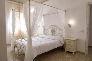 ein Schlafzimmer mit einem weißen Himmelbett und einer Kommode in der Unterkunft AFFITTACAMERE I PACIORRA in Favignana