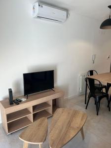sala de estar con TV y mesa con sillas en Departamento moderno con parrilla privada para 3 en Salta