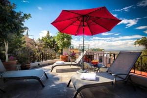 a patio with two chairs and a red umbrella at ELEGANT HOME WITH STUNNING VISTAS - CASA VALENTINA in San Miguel de Allende