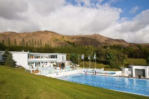 a hotel with a large swimming pool in front of a building at Heiðarbrún in Hveragerði