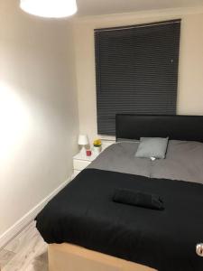 ein Schlafzimmer mit einem Bett mit einer schwarzen Decke und einem Fenster in der Unterkunft Four bedroom property for 10 guests, great location Aldgate E1 close to Tower bridge in London
