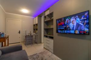 uma sala de estar com uma televisão de ecrã plano na parede em Pôr do sol 18º andar vista da cidade CENTRAL, Garagem NOVO em Passo Fundo
