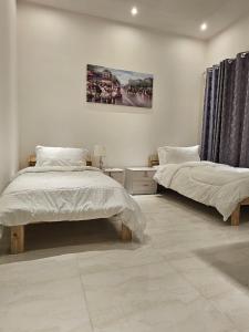 a bedroom with two beds and a painting on the wall at تاج الكورنيش عجمان in Ajman 