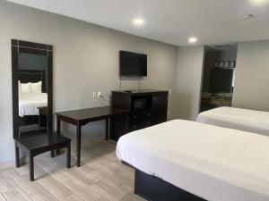 a hotel room with two beds and a desk with a television at Falcon Executive Inn in Zapata