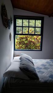 um quarto com uma cama e uma janela em Chalé das Montanhas - Cachoeira particular dentro da hospedagem em Nova Friburgo