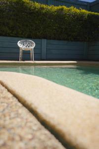 une chaise blanche assise à côté de la piscine dans l'établissement Coolum Budget Accommodation, à Coolum Beach