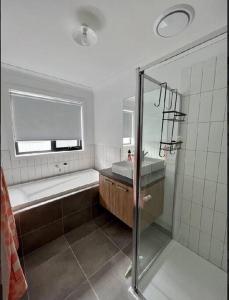 y baño con ducha, bañera y lavamanos. en Wonderful Jubilee Estate House, en Wyndham Vale