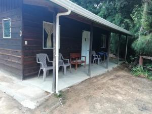 a porch of a cabin with chairs and a table at Miriam'S Quetzals lodge in San Gerardo de Dota