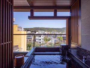 a bathroom with a tub with a view of a city at Sora Niwa Terrace Kyoto Bettei in Kyoto