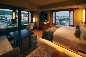 a hotel room with a bed and a desk and windows at Sora Niwa Terrace Kyoto Bettei in Kyoto
