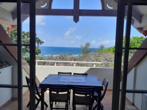 a table and chairs on a balcony with a view of the ocean at TROPIC Appartements PREMIUM village vacances vue mer Guadeloupe St Anne avec piscine in Sainte-Anne +113 photos
