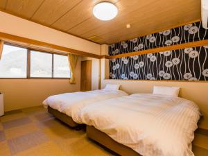a bedroom with two beds and a wall with flowers at Japanese Onsen Ryokan Kohakuen in Fuefuki