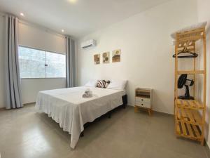 Un dormitorio con una cama con sábanas blancas y una escalera en Casa do Villas - Arraial d'Ajuda, en Arraial d'Ajuda