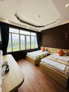 een slaapkamer met 2 bedden en een groot raam bij Minh Hoang Hotel & Homestay in Cao Bằng