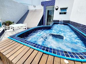 a swimming pool on a deck with a house at Cobertura em Ondina in Salvador