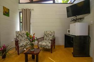 a living room with two chairs and a flat screen tv at Riverside Villas in Manuel Antonio