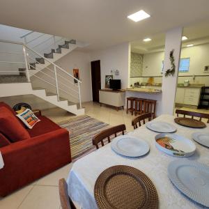 a living room with a table and a red couch at Casa confortável pertinho da praia com garagem e quintal in Rio das Ostras