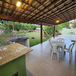 een patio met een tafel en stoelen onder een pergola bij Casa confortável pertinho da praia com garagem e quintal in Rio das Ostras