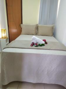 a bed with a towel and flowers on it at Pousada Barreirinhas House in Barreirinhas