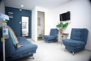 - un salon avec 2 chaises bleues et une télévision dans l'établissement casa nogal, à Medellín