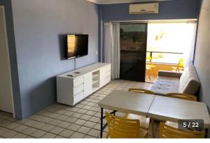 ein Wohnzimmer mit einem Esstisch und einem TV in der Unterkunft Resort flat Gavôa in Igarassu