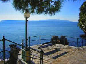 a bench next to the ocean with a lamp at Apartments Villa Dinka in Opatija