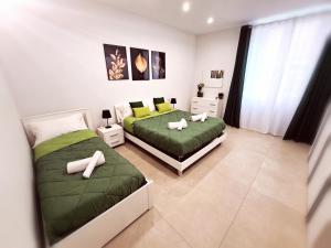 2 camas en un dormitorio con sábanas verdes en Le Popolari - Appartamento, en Bitonto